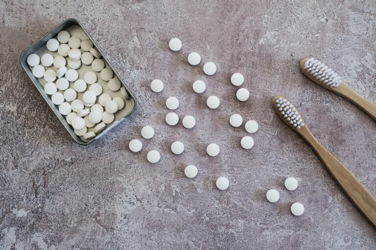 High angle close up of two wooden toothbrushes and pills in metal box.