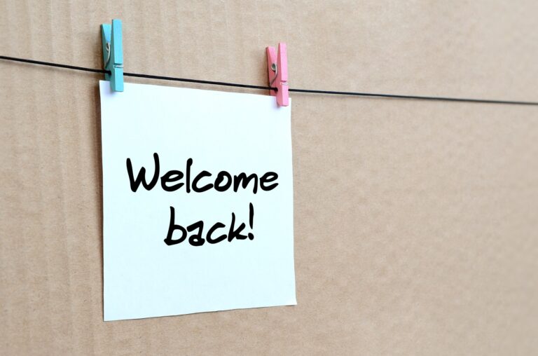 Welcome back! Note is written on a white sticker that hangs with a clothespin on a rope on a